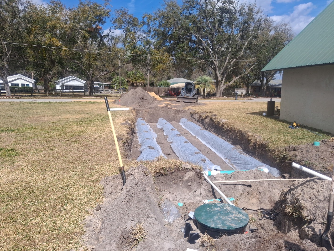 Open drain field trenches with leaching chambers and septic tank lids on a residential lot